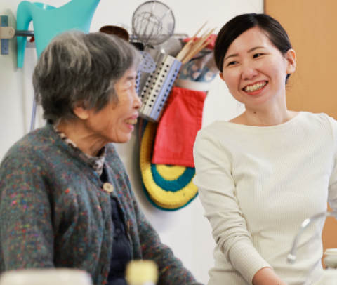 スタッフと入居者がコミュニケーションを取っている様子。笑顔で楽しそうに交流している。